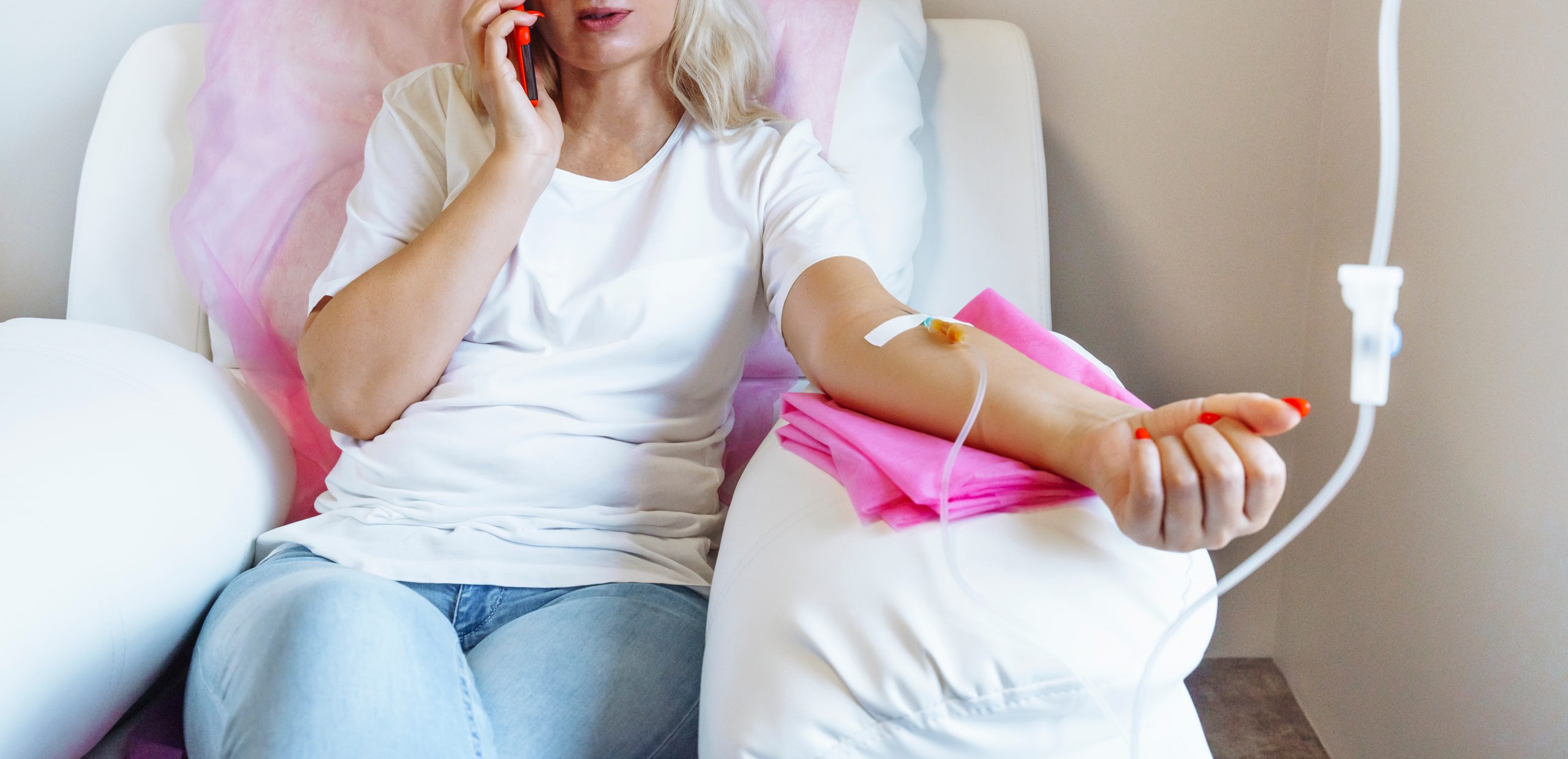 Woman in hospital talking at mobile phone while receiving wellness services.